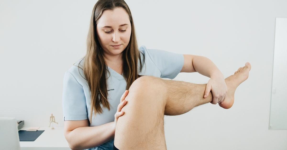 A physiotherapist assisting a patient's leg therapy session indoors, focusing on rehabilitation.