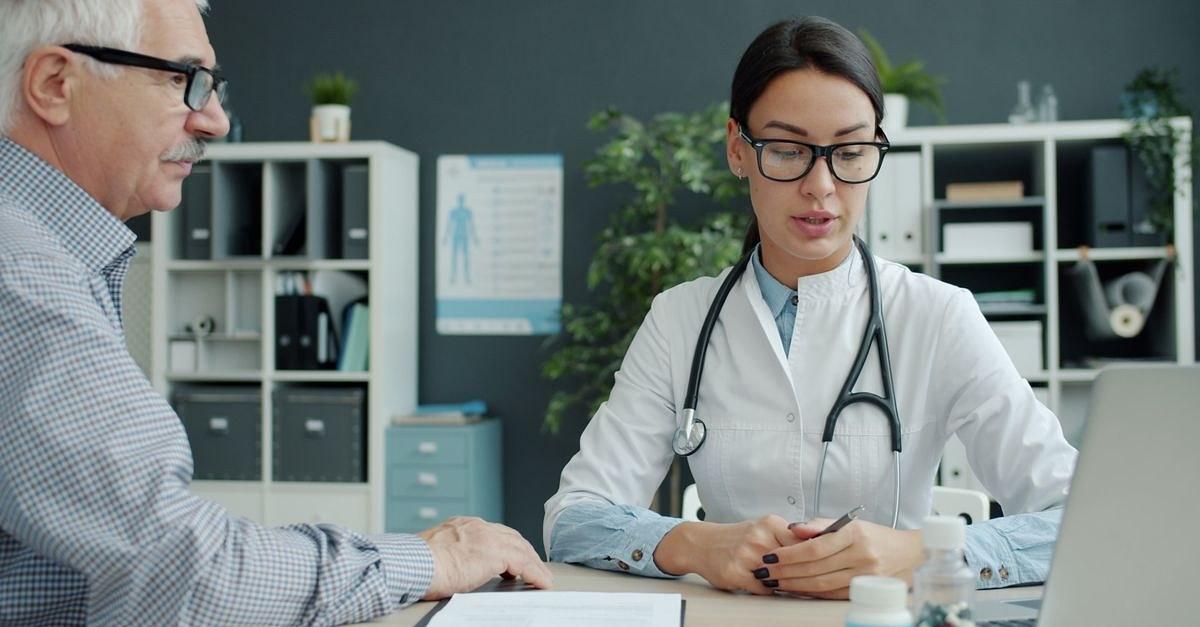 Medical professional discusses health with senior man in modern office setting.