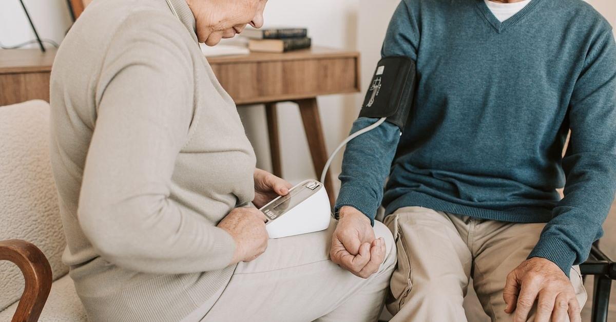 Senior couple at home measuring blood pressure for health check.