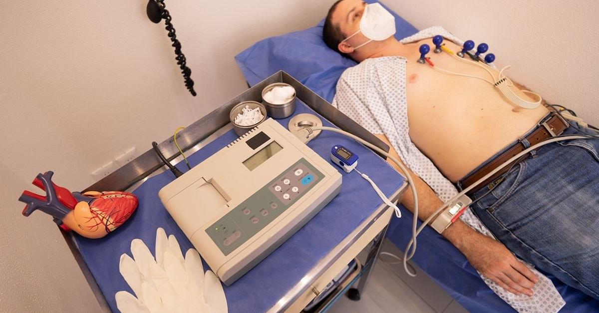 A man undergoing a cardiology exam with an ECG machine in a medical clinic.