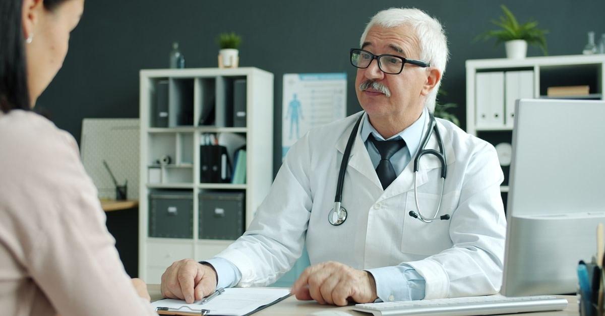 Senior doctor discussing health with patient in a modern medical office.
