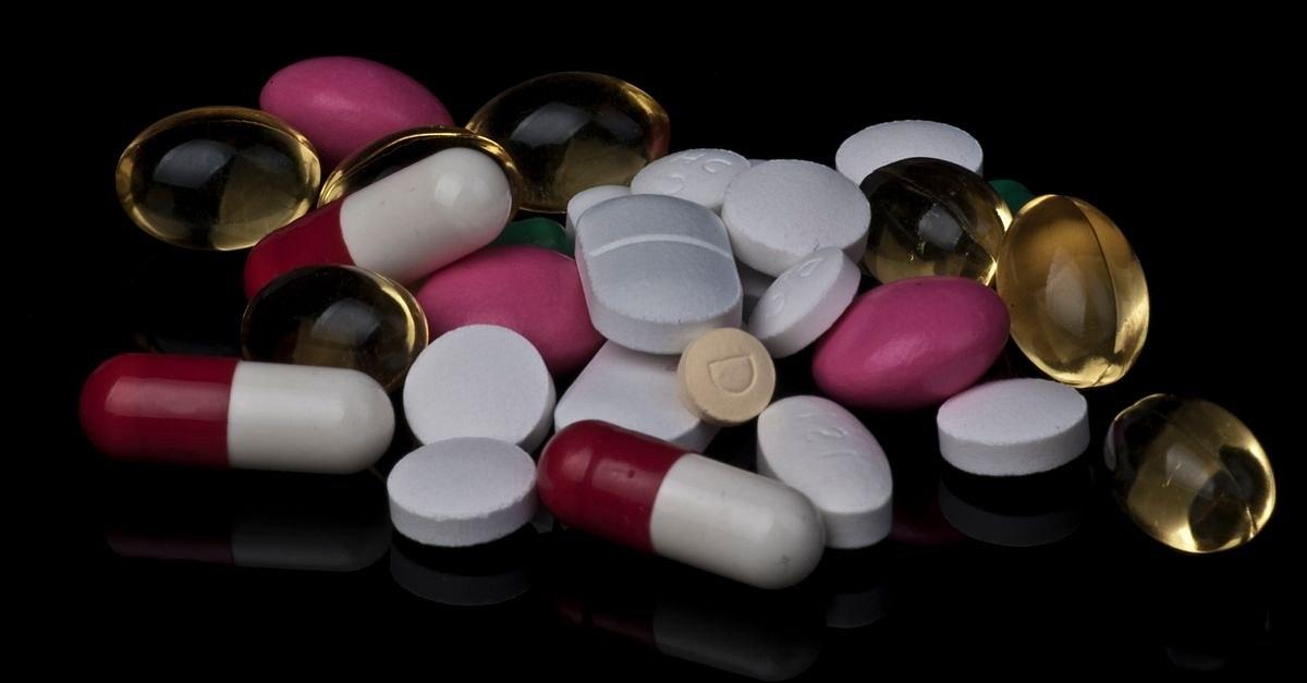 Close-up of various colorful pills and capsules on a black background.