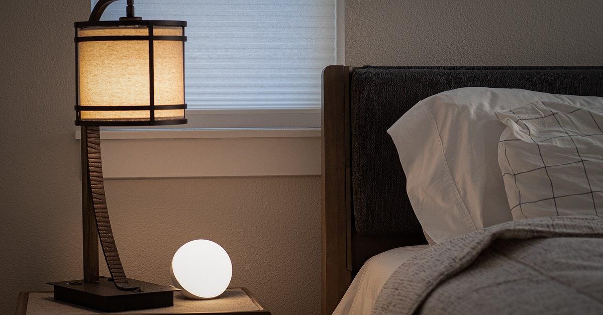 Serene and inviting bedroom interior featuring a warm-lit lamp and cushioned bed.
