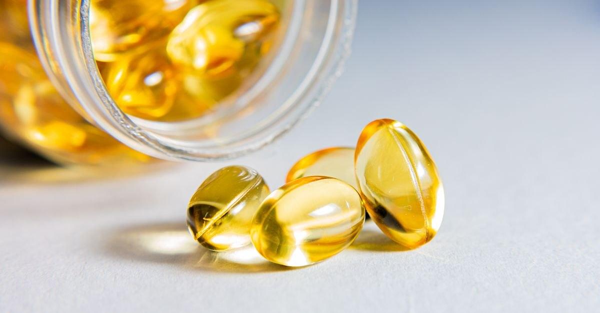 High-quality close-up of transparent softgel capsules spilled from a glass jar, showcasing vitamins or supplements.
