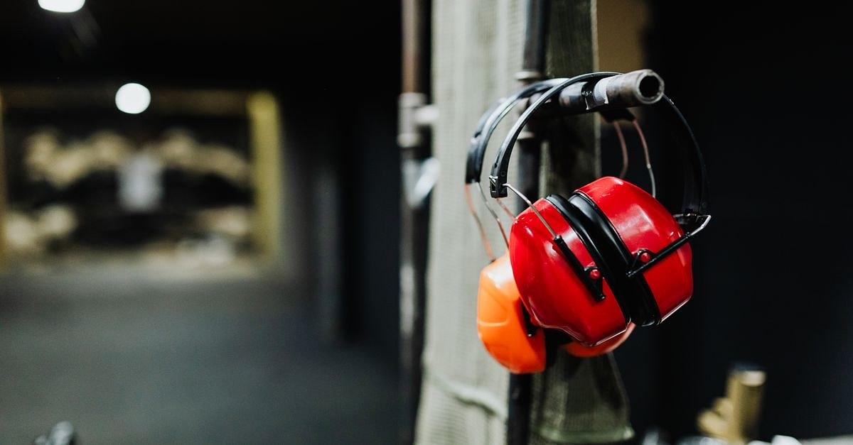 Red ear muffs hanging at an indoor shooting range, offering essential safety gear.