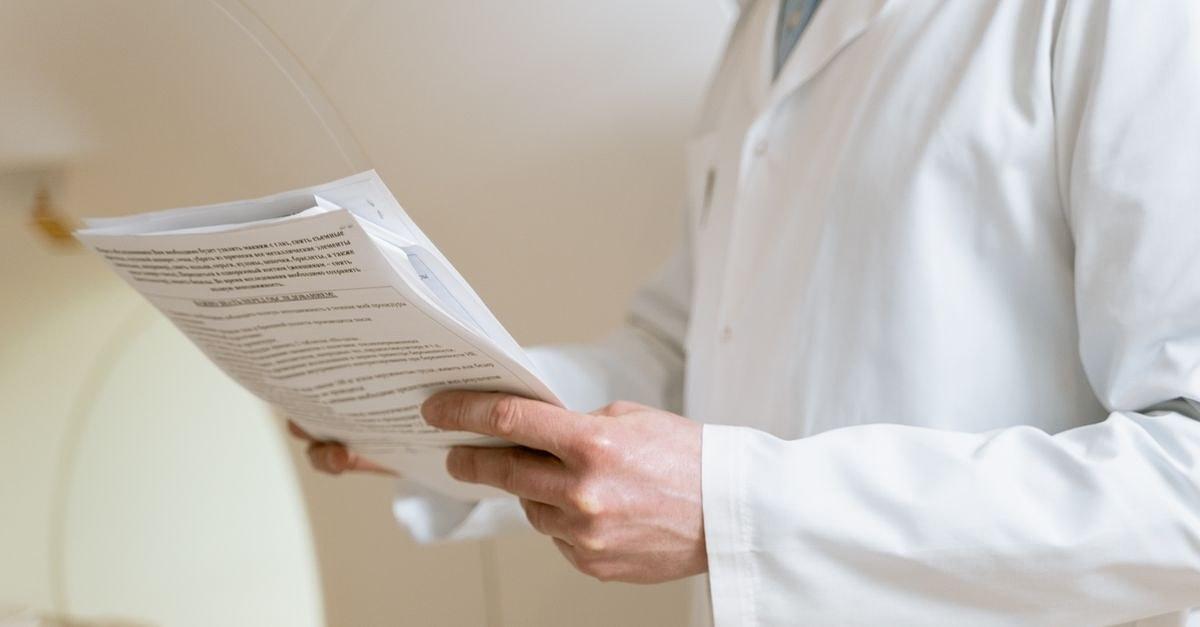 Doctor in a white coat examining medical papers in a healthcare setting.
