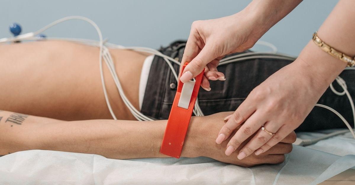 Close-up of a medical check-up using electrodes and an arm band in a clinical setting.
